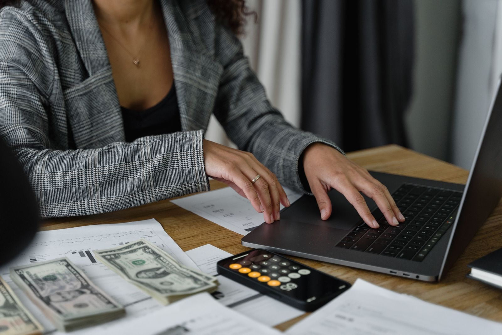 A person working out costs with a calculator and laptop, representing CAPM certification cost.