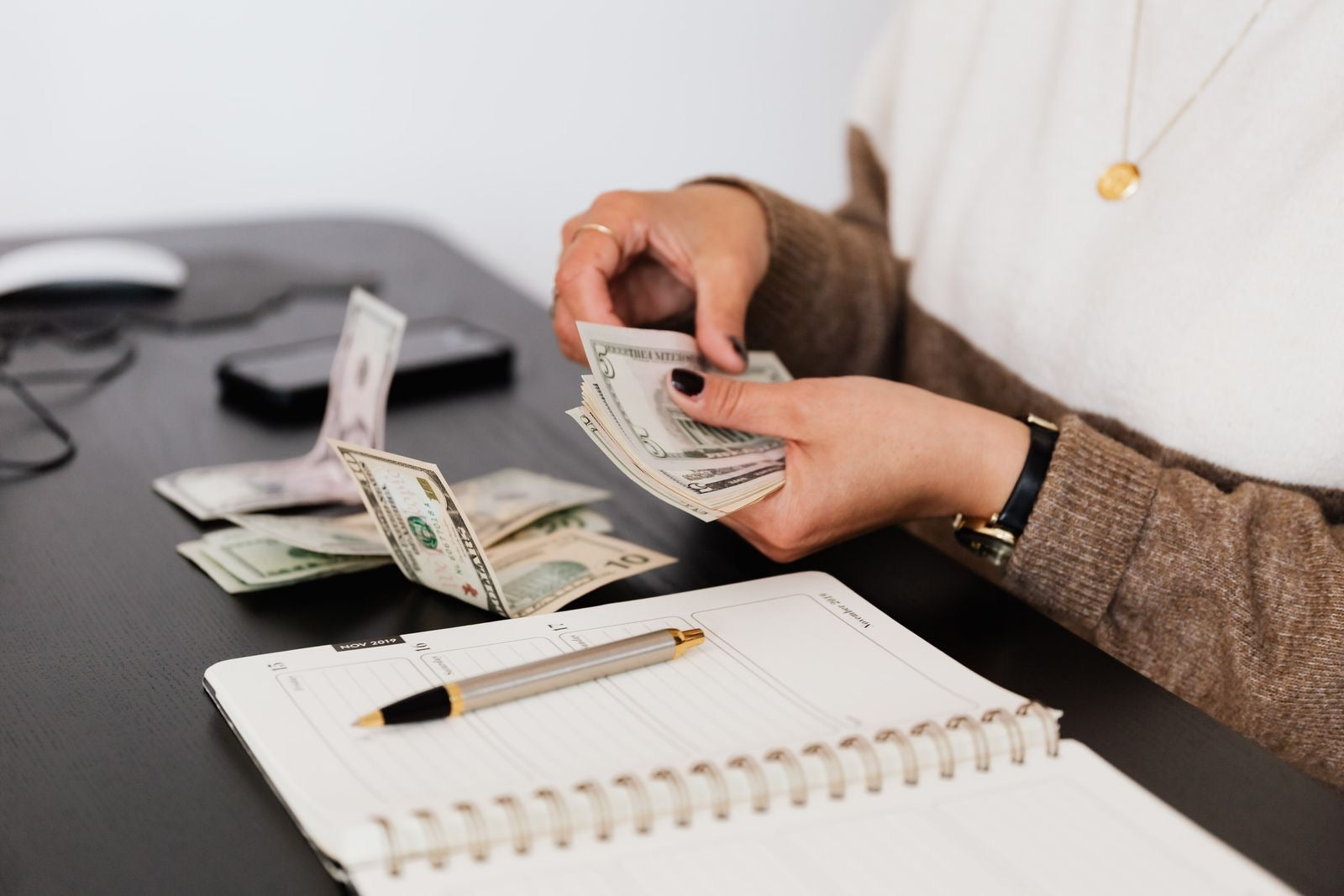 A professional counting money over a planner, setting funds aside as reserves for project risks.