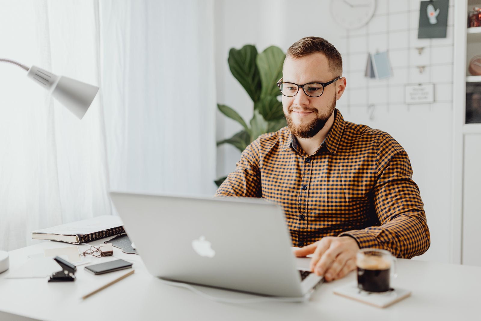 A professional in glasses studying on a laptop in a home office, preparing for the PMP exam.