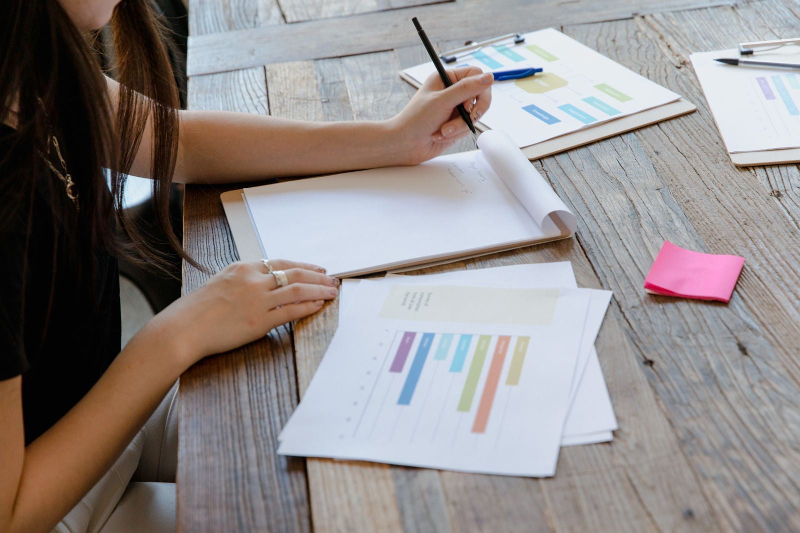 A professional writing notes among charts and documents while preparing for the PMP exam.