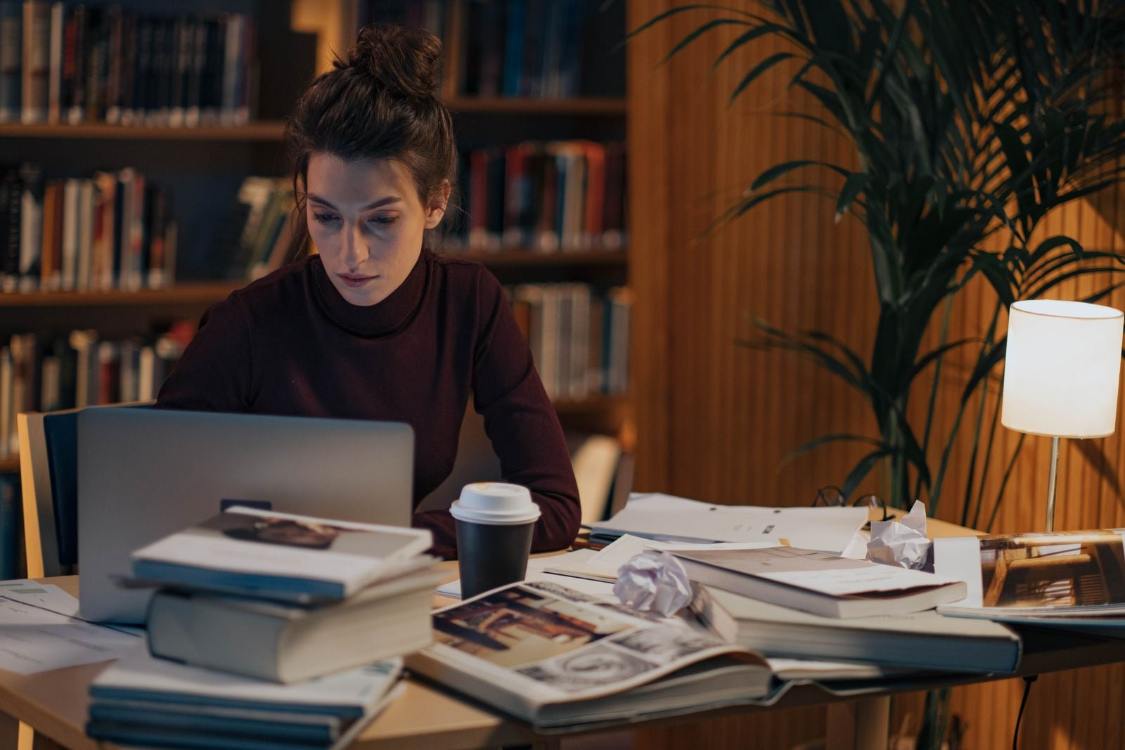 A project manager studying for the PMP at a desk with books, a laptop, and coffee.