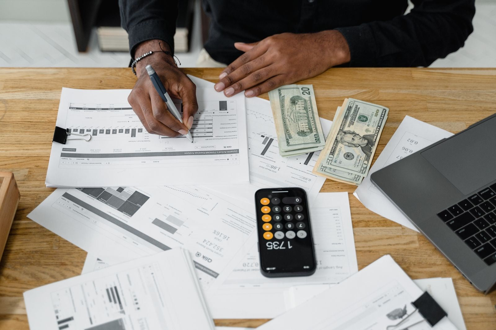 A professional building a project budget with financial reports and a calculator, representing the project budget and cost baseline.