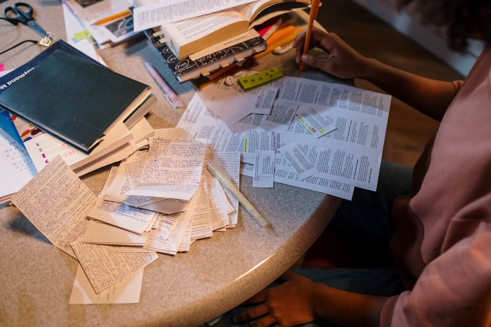 A student organizing notes and books while preparing for an exam, representing a structured CAPM study plan.