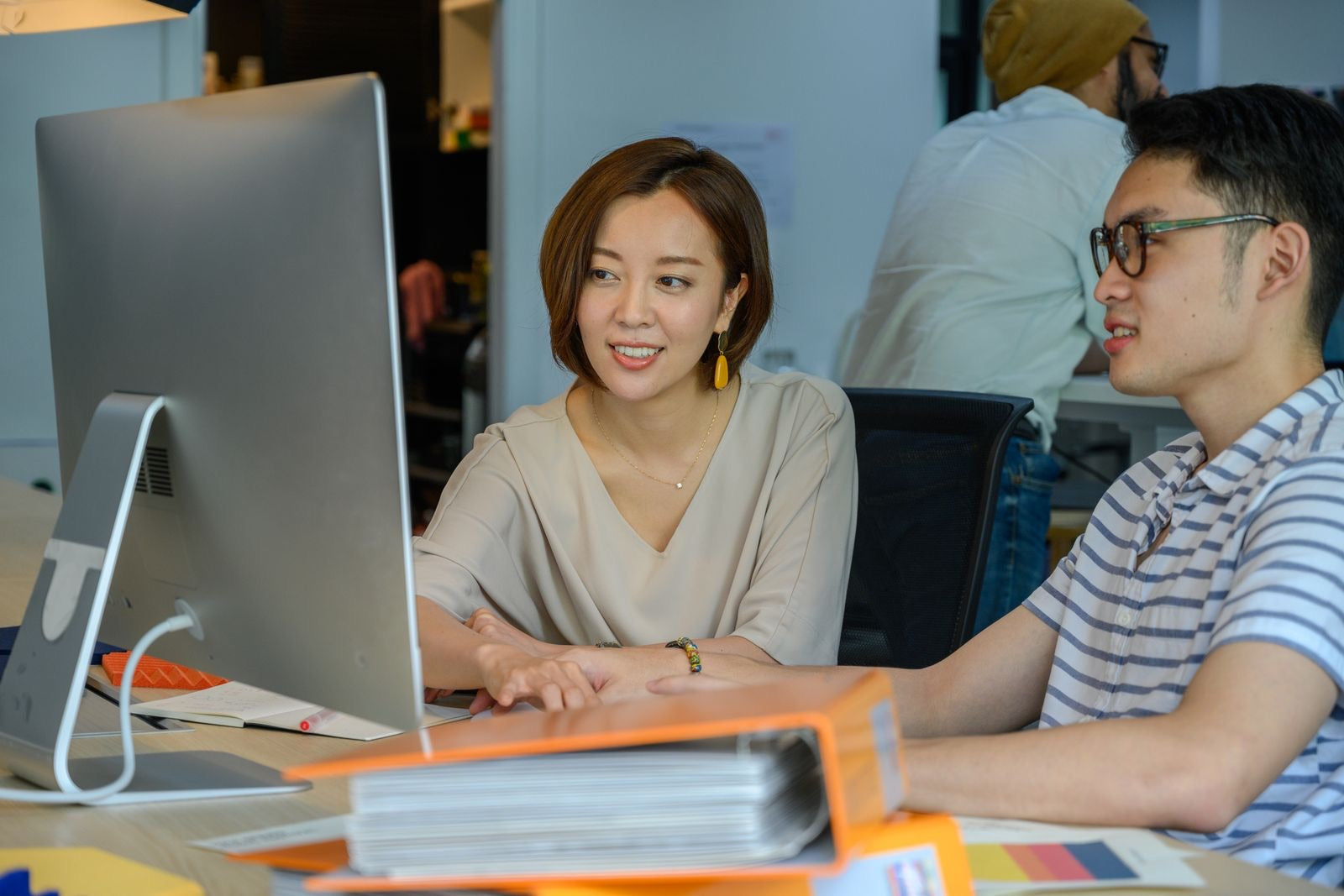 Two colleagues reviewing a project timeline together at a monitor, planning the schedule bar by bar.