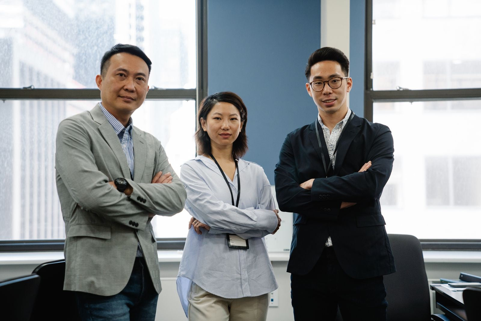Three project management professionals standing confidently with arms crossed.